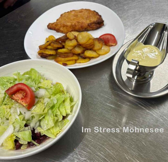 Schnitzel Wiener Art mit Bratkartoffeln, Salat und Sauce Hollandaise.