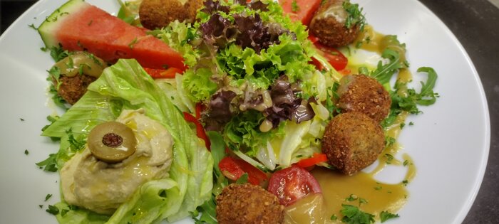Falafelbällchen mit Hummus, auf buntem Salat (vegan)